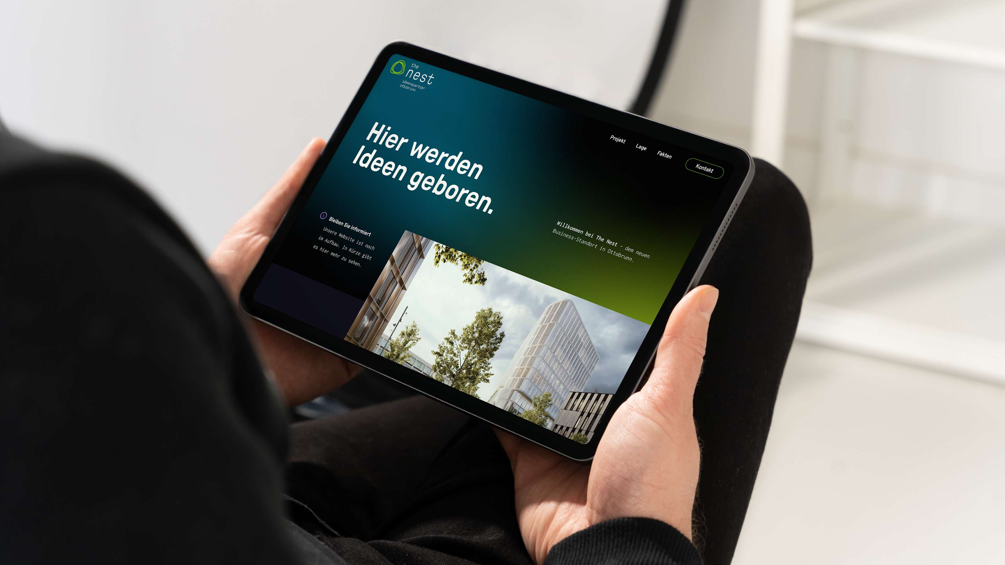 Jemand hält ein Tablet in den Händen, auf dem die Startseite von The Nest zu sehen ist